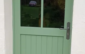 Porte d’entrée PVC verte avec vitrage supérieur et panneaux pleins, finition classique et soignée