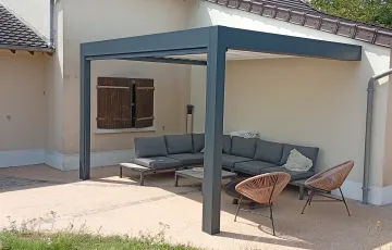 Pergola aluminium adossée avec structure grise, aménagée en terrasse avec salon de jardin