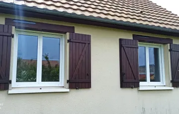 Fenêtres PVC blanches avec volets battants marron sur façade de maison traditionnelle