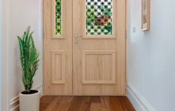 Porte d’entrée intérieure en bois clair avec vitrage décoratif, style chaleureux et naturel